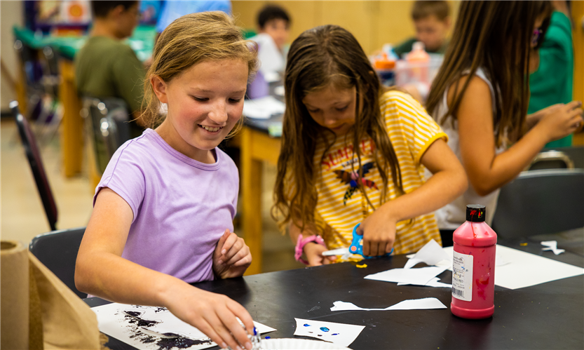 Two girls paint while at a summer camp